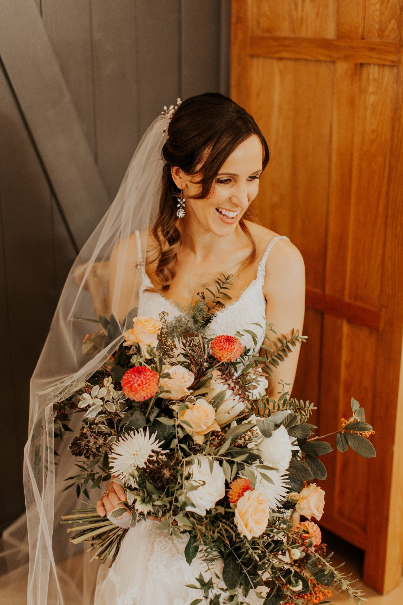 Bride with autumn bouquet of rose hips, proteas dahlias, and foraged greenery by Kim Chan Events